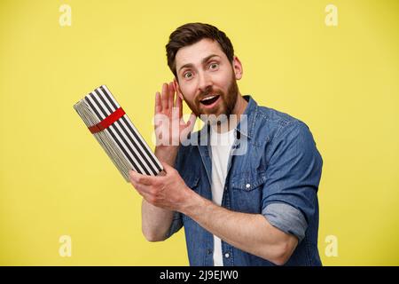 Überrascht stattlichen Mann zuhören, was klappert in Geschenkbox. Erraten Sie, was drin ist Stockfoto