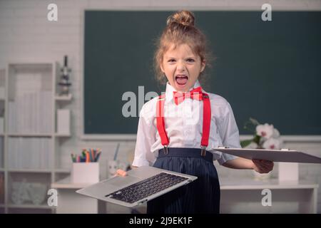 Wütend Kind gebrochen Online-Laptop in der Schule. Bad girl Student in Opposition Fernbildung. Beschädigte Computertechnologie wird zerstört. Kinder haben Probleme mit Stockfoto