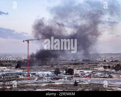 Schwarzer Rauch wabert aus einem kleinen Gebäude in einem Industrie- und Lagerviertel einer Stadt in der Region Negev in Israel Stockfoto