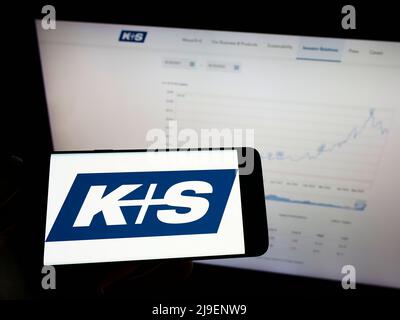 Person mit Mobiltelefon und Logo des deutschen Bergbauunternehmens KS AG (K plus S) auf dem Bildschirm vor der Business-Webseite. Konzentrieren Sie sich auf die Telefonanzeige. Stockfoto