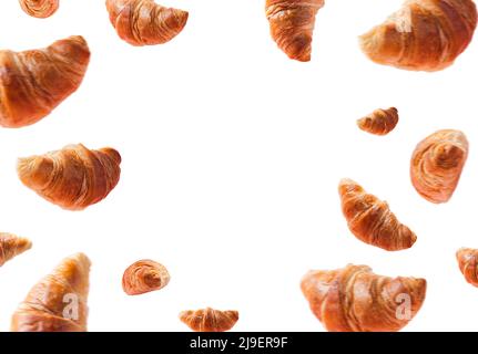 Viele frisch gebackene Croissants schweben oder fliegen. Croissants isoliert auf weißem Hintergrund mit Kopieplatz in der Mitte. Levitation-Szene. Werbung für Bäckerei, Süßwaren. Kreatives Frühstück Stockfoto