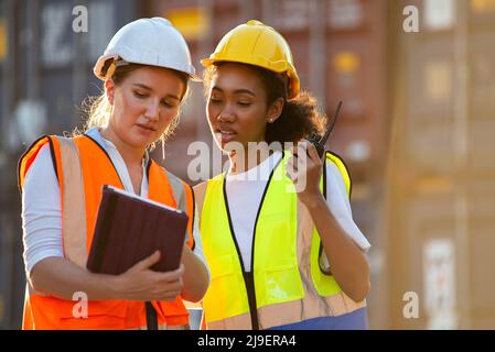 Geschäftsfrau und Logistikarbeiterin beim Überprüfen der Container-Box und beim Laden der Produkte im Computer des Frachtschiffes Cargo am Container. Stockfoto