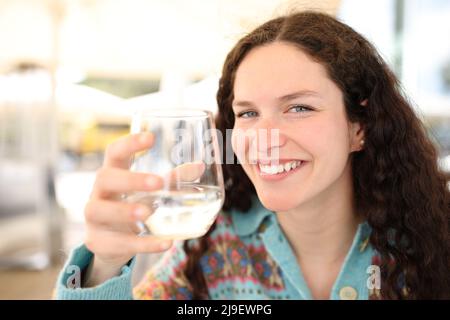 Eine glückliche Frau, die Wasserglas hält, blickt auf eine Barterrasse Stockfoto