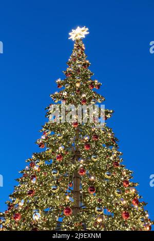 Weihnachtsbaum, beleuchtet in der Nacht, dekoriert mit Lichtern und Glaskugeln. Stockfoto