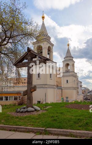 Gedenkkreuz im Innenhof der Kirche des heiligen Wladimir in den Alten Gärten vor dem Hintergrund des Johannes-der-Täufer-Klosters, Moskau. Stockfoto