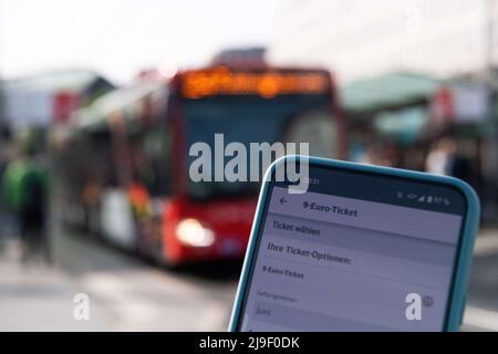 Bremen, Deutschland. 23.. Mai 2022. Auf einem Handy wird die Buchungsseite für das 9-Euro-Ticket mit einem roten Bus im Hintergrund aufgerufen. Nach der Zustimmung von Bundestag und Bundesrat ist nun der Weg für das 9-Euro-Ticket frei. Ab Juni können die Verbraucher damit im öffentlichen Nahverkehr (ÖPNV) günstig in ganz Deutschland reisen. Das Ticket wird in den jeweiligen Apps, Fahrkartenautomaten und Kundenzentren aller Verkehrsunternehmen in Deutschland angeboten. Quelle: Melissa Erichsen/dpa/Alamy Live News Stockfoto