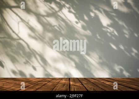 Hintergrund der Schattentabelle. Weiße Wand mit Schatten Pflanzen und Baum in Sonnenlicht mit Holz rustikalen Tisch. Hochwertige Fotos Stockfoto