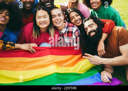 Verschiedene Menschen, die Spaß daran haben, die LGBT-Regenbogenflagge im Freien zu halten Stockfoto