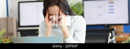 Eine Frau im Büro leidet unter Kopfschmerzen Stockfoto
