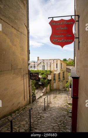 Saint-Emilion, Frankreich - 10. Mai 2022: Malerische Dorfstraße in Saint-Emilion mit einem französischen Macarons-Laden und einer Bäckerei im Vordergrund Stockfoto