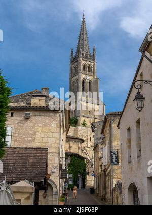 Saint-Emilion, Frankreich - 10. Mai 2022: Schmale Straße im Dorfzentrum von Saint-Emilion mit dem Glockenturm der Stiftskirche im Hintergrund Stockfoto