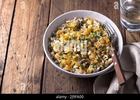 Traditionelles nahöstliches Gericht, Mujadara aus Linsen, Reis und gebratenen Zwiebeln auf Holztisch, Draufsicht, selektiver Fokus, freier Platz Stockfoto