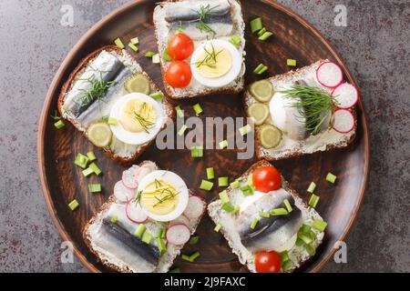 Estnische traditionelle Delikatesse Kiluvoileib Sandwich mit Fisch, Ei und Butter Nahaufnahme in einem Teller auf dem Tisch. Horizontale Ansicht von oben Stockfoto