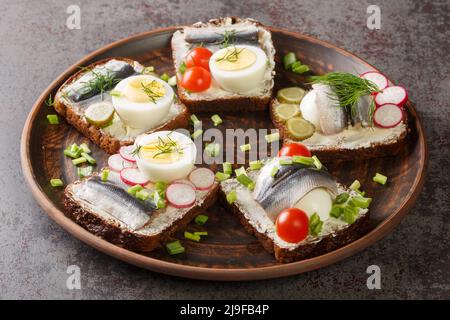 Estnische traditionelle Delikatesse Kiluvoileib Sandwich mit Fisch, Ei und Butter Nahaufnahme in einem Teller auf dem Tisch. Horizontal Stockfoto