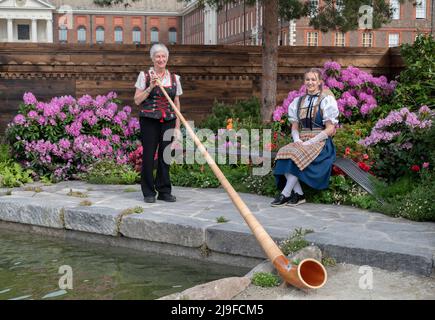 Royal Hospital, Chelsea, London, Großbritannien. 23 Mai 2022. Die RHS Chelsea Flower Show öffnet für die Presse zurück in seinem normalen Early Summer Slot läuft vom 24-28. Mai. Bild: Ein Swiss Sanctuary Show Garden mit Alpenhorn-Spieler in traditioneller schweizer Kleidung. Quelle: Malcolm Park/Alamy Live News. Stockfoto