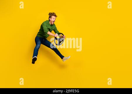 In voller Länge Foto von ziemlich beeindruckt Kerl gekleidet Pullover Fahren Fahrzeug leeren Raum isoliert gelbe Farbe Hintergrund Stockfoto