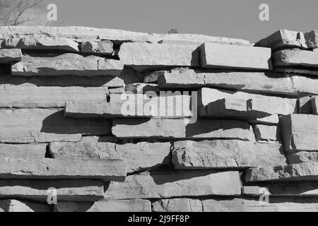 Eine hohe Wand aus Steinen für einen rustikalen Effekt in Schwarz und Weiß. Stockfoto