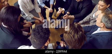 Ein vielfältiges Team aus jungen und reifen Menschen, die bei einem Unternehmens- oder Geschäftstreffen im Kreis sitzen Stockfoto