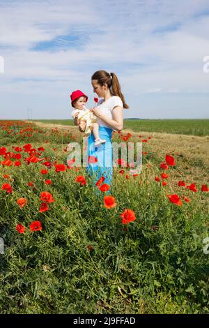 Eine Mutter, die ihrer Tochter eine Mohnblume zeigt Stockfoto