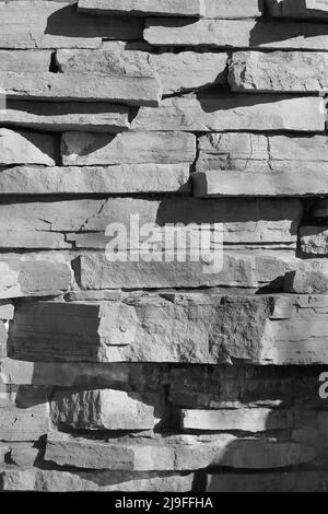 Eine hohe Wand aus Steinen für einen rustikalen Effekt in Schwarz und Weiß. Stockfoto