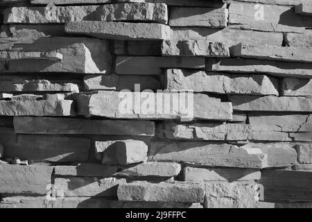 Eine hohe Wand aus Steinen für einen rustikalen Effekt in Schwarz und Weiß. Stockfoto