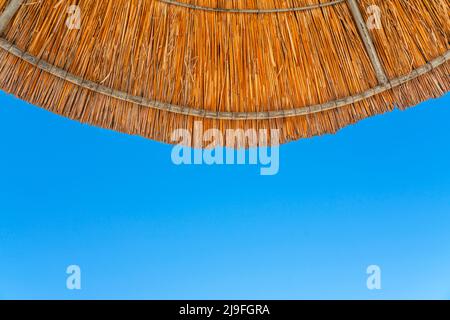 Sonnenschirm gegen den blauen Himmel am Strand. Ansicht von unten. Stockfoto