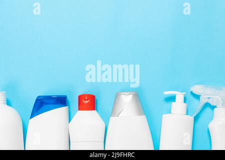 Flaschen mit Haushaltschemikalien sprühen und Schwämme zum Reinigen und Waschen auf einem blauen isolierten Hintergrund. Reinigungskonzept. Banner. Stockfoto