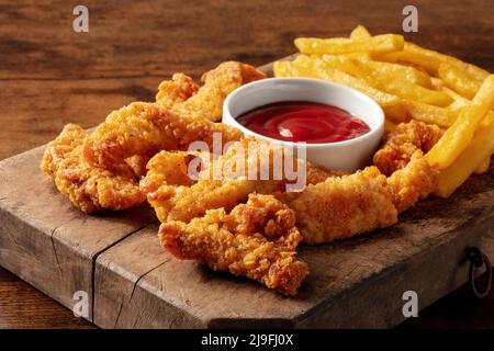 Hähnchenschaufeln, zerschlagen und gebraten knusprige Keile, mit einer bbq-Sauce und Kartoffeln, auf einem dunklen rustikalen Holztisch Stockfoto