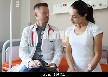 Der männliche Arzt kommuniziert mit der weiblichen Patientin in der Klinik Stockfoto