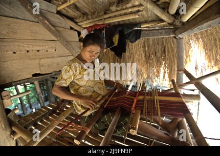 Eine Frau, die in einem Haus im traditionellen Dorf Praijing in Tebara, Waikabubak, West Sumba, Ost-Nusa Tenggara, Indonesien webt. Stockfoto