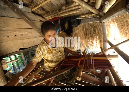 Eine Frau, die in einem Haus im traditionellen Dorf Praijing in Tebara, Waikabubak, West Sumba, Ost-Nusa Tenggara, Indonesien webt. Stockfoto