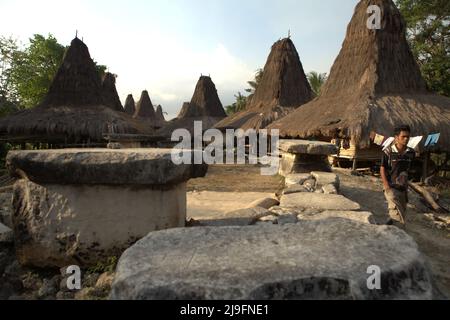 Ein Mann, der auf der Seite von megalithischen Gräbern im traditionellen Dorf Praijing in Tebara, Waikabubak, West Sumba, Ost-Nusa Tenggara, Indonesien, läuft. Stockfoto