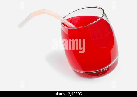 Roter Saft und eine Tube in einem Glas auf weißem Hintergrund. Selektiver Fokus Stockfoto