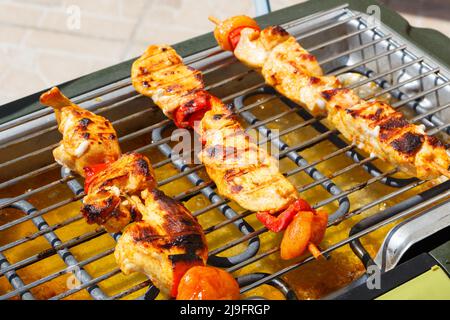 Marinierter Hähnchenbrochette auf dem Gitter eines elektrischen Grills Stockfoto