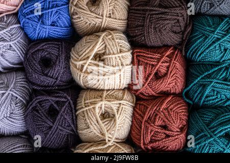 Bunte Wollkugeln auf Holztisch. Verschiedene Garnkugeln, Ansicht von oben. Stockfoto
