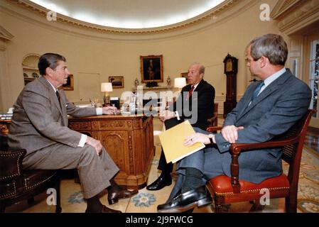 Der linke US-Präsident Ronald Reagan trifft am 14. November 1984 im Oval Office des Weißen Hauses in Washington, DC, mit dem US-Außenminister George Schultz, Mitte, und Robert McFarlane, dem Assistenten des Präsidenten für nationale Sicherheitsangelegenheiten, rechts, zusammen. Obligatorische Gutschrift: Jack Kightlinger/White House über CNP Stockfoto