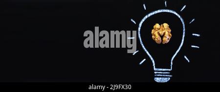 Gezeichnete Glühbirne mit schmackhaftem Nussbaum auf schwarzem Hintergrund Stockfoto