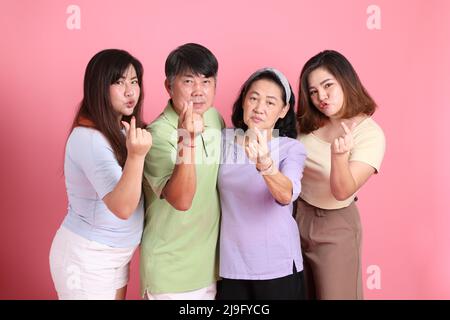 Die glückliche asiatische Familie steht auf dem rosa Hintergrund. Stockfoto