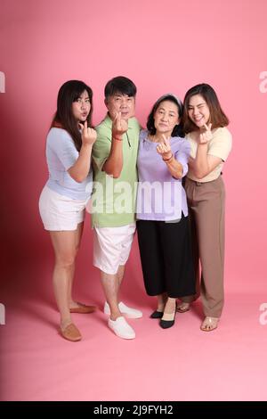Die glückliche asiatische Familie steht auf dem rosa Hintergrund. Stockfoto