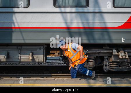 Eisenbahnmechaniker, der Wartungsarbeiten am Bahnhof Nowosibirsk-Glavny in Nowosibirsk, Russland, vornimmt, einem wichtigen Halt entlang der Transsibirischen Eisenbahn. Stockfoto