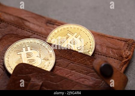 Geldbörse aus braunem Leder mit Krypto-Curreency und einer Goldmünze mit Bitcoin. Digitales Finanzierungskonzept Stockfoto