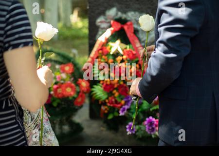 Blumen auf dem Denkmal. Menschen legen weiße Blumen auf die Grabstätte. Ein unvergessliches Ereignis. Tag des Sieges in Russland. Ein Zeichen des Respekts für den gefallenen Krieg Stockfoto