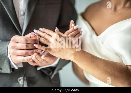 Das Brautpaar tauscht Ringe aus, während der Bräutigam einen Ring auf den Finger einer Braut legt. Stockfoto