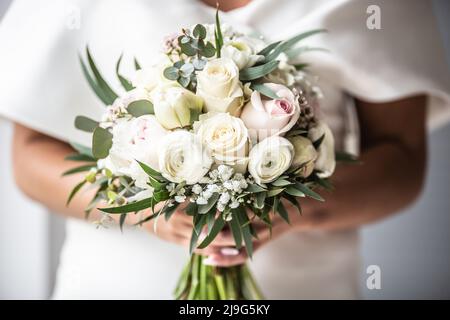 Detail der Braut mit weißen Hochzeitsblumen Bouquette in ihren Händen. Stockfoto