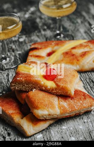 Nahaufnahme von einigen Coca de sant joan, einem süßen flachen Kuchen aus katalonien, spanien, der normalerweise am saint johns Eve gegessen wird, und einigen Gläsern mit catala Stockfoto