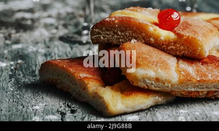 Nahaufnahme von einigen Stücken Coca de sant joan, einem typischen süßen flachen Kuchen aus katalonien, spanien, gegessen am st. johns Vorabend, auf einem grauen rustikalen Holztisch, Stockfoto