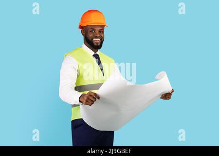 Lächelnder Afroamerikanischer Auftragnehmer, Der Blueprints Hält, Während Er Isoliert Auf Blauem Hintergrund Steht Stockfoto