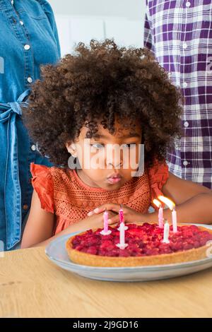 Mädchen bläst Kerzen auf Kuchen Stockfoto