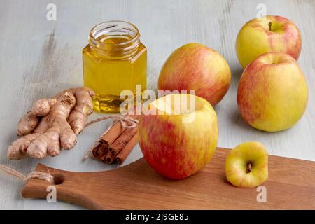 Äpfel, Zimtstangen, Ingwer und Honig auf einem hellblauen Holztisch. Kochen gebackene süße Äpfel Stockfoto