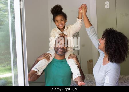 Lächelnde Familie sitzt zusammen auf dem Bett Stockfoto